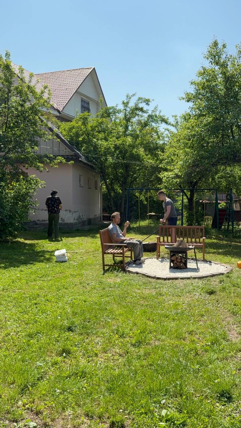 Газон перед домом, люди у мангала
